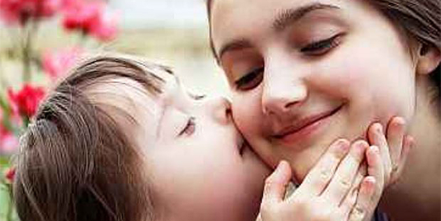 Child with Down syndrome kissing the cheek of an adult. 